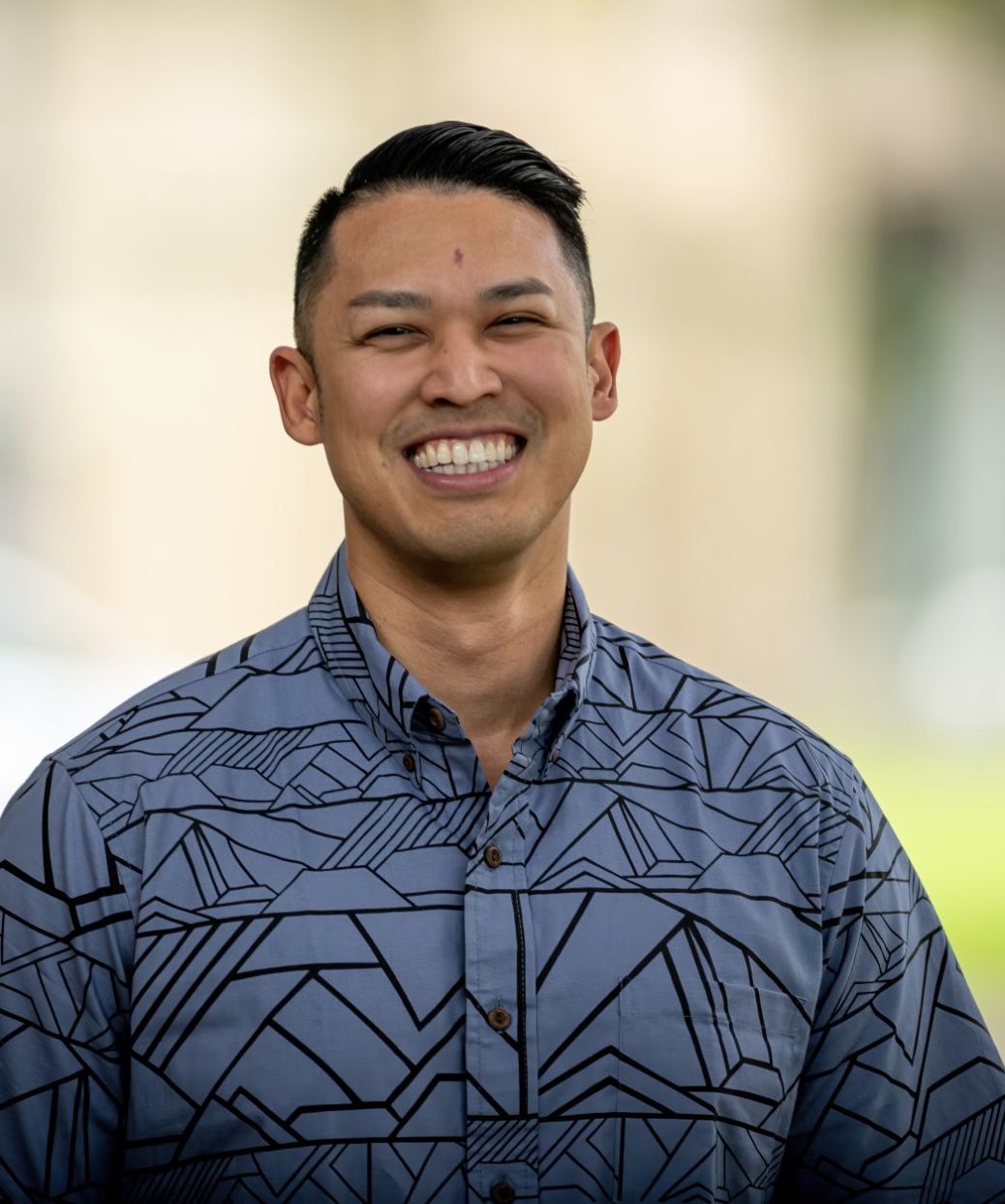 Micah Aiu smiling in a blue aloha shirt.
